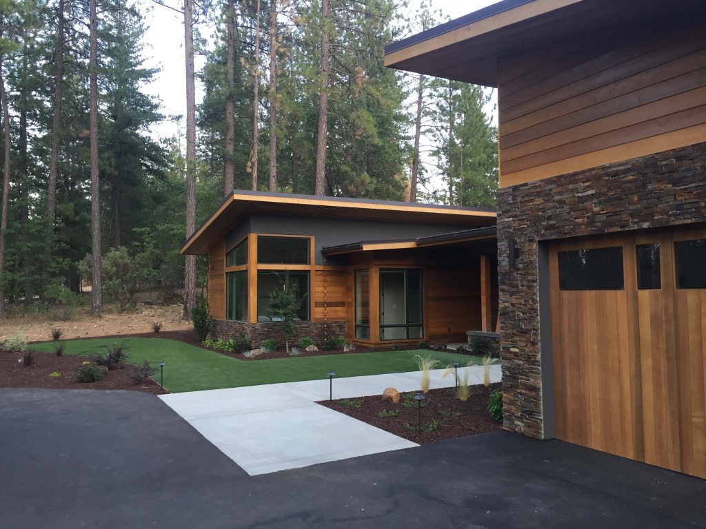 Residential concrete driveway blending seamlessly with a wooded landscape, designed and installed by Aronson Landscape